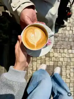 Cappuccino held over Prague cobblestones