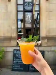 Orange Claudia Coffee drink held in front of the window